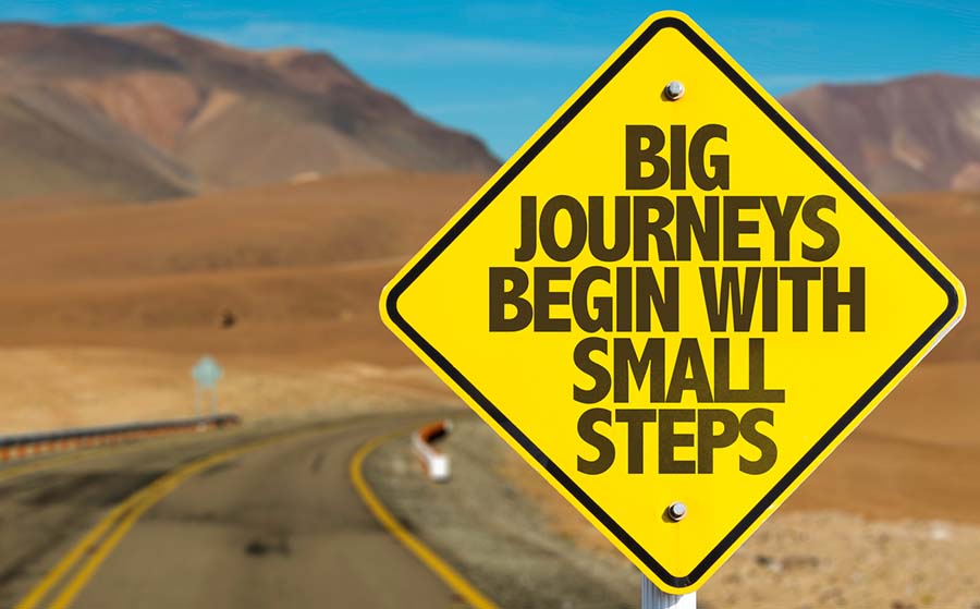 Big Journeys Begin With Small Steps sign with sky background