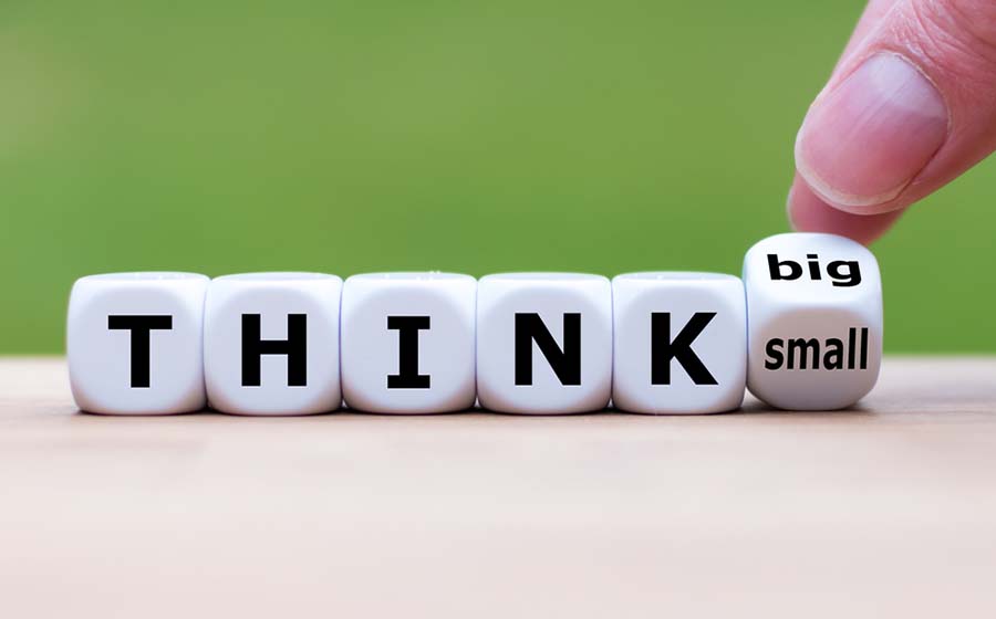 Hand turns a dice and changes the expression "think big" to "think small"