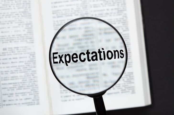 dictionary with magnifying glass with word expectations in center