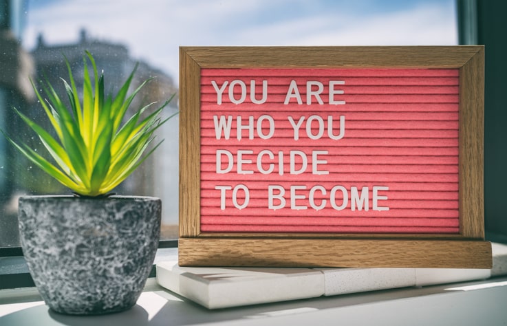 sign on desk reading you are who you decide to become.